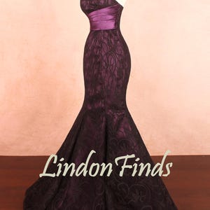 Puede incluir: Vestido largo sin tirantes en morado oscuro, con corpiño ajustado con banda de satén y falda acampanada. El vestido está cubierto con encaje negro, creando un efecto texturizado. El texto "Lindon Finds" es visible.
