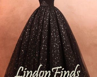 May include: A black off-the-shoulder gown with a sparkling star pattern. The dress features a fitted bodice and a full, flowing skirt. The text "Lindon Finds" is displayed on the skirt.