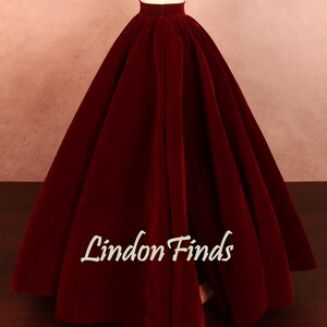 May include: A full, floor-length burgundy velvet skirt on a mannequin. The skirt has a high waist and a wide, flowing silhouette. The text "Lindon Finds" is printed on the skirt.
