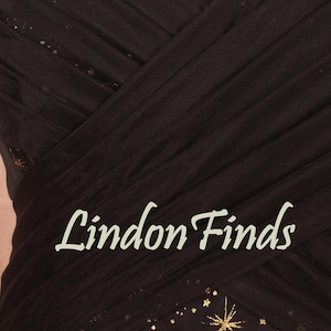 May include: Close-up of a dark brown dress with a layered, pleated design. The dress has a subtle sparkle with gold star accents. The text "Lindon Finds" is displayed in a cursive font.