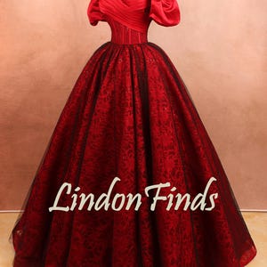 May include: A formal red gown with an off-the-shoulder neckline and a full skirt. The bodice is fitted, and the skirt features a floral pattern. The dress has a black underlay and the text "Lindon Finds".