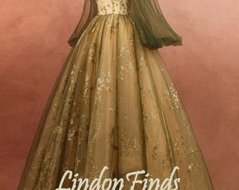 May include: A formal gown with an off-the-shoulder neckline and long, sheer sleeves. The bodice is a light cream color with gold floral embroidery. The skirt is a flowing, champagne color with gold accents. The text "Lindon Finds" is visible.