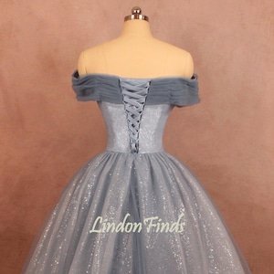 K&ouml;nnte beinhalten: Ein hellblaues, schulterfreies Ballkleid mit Schn&uuml;rung im R&uuml;cken und einem glitzernden T&uuml;llrock. Das Kleid befindet sich auf einer Puppe.