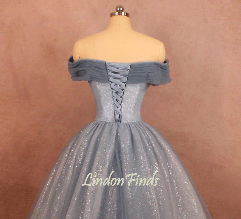 K&ouml;nnte beinhalten: Ein hellblaues, schulterfreies Ballkleid mit Schn&uuml;rung im R&uuml;cken und einem glitzernden T&uuml;llrock. Das Kleid befindet sich auf einer Puppe.