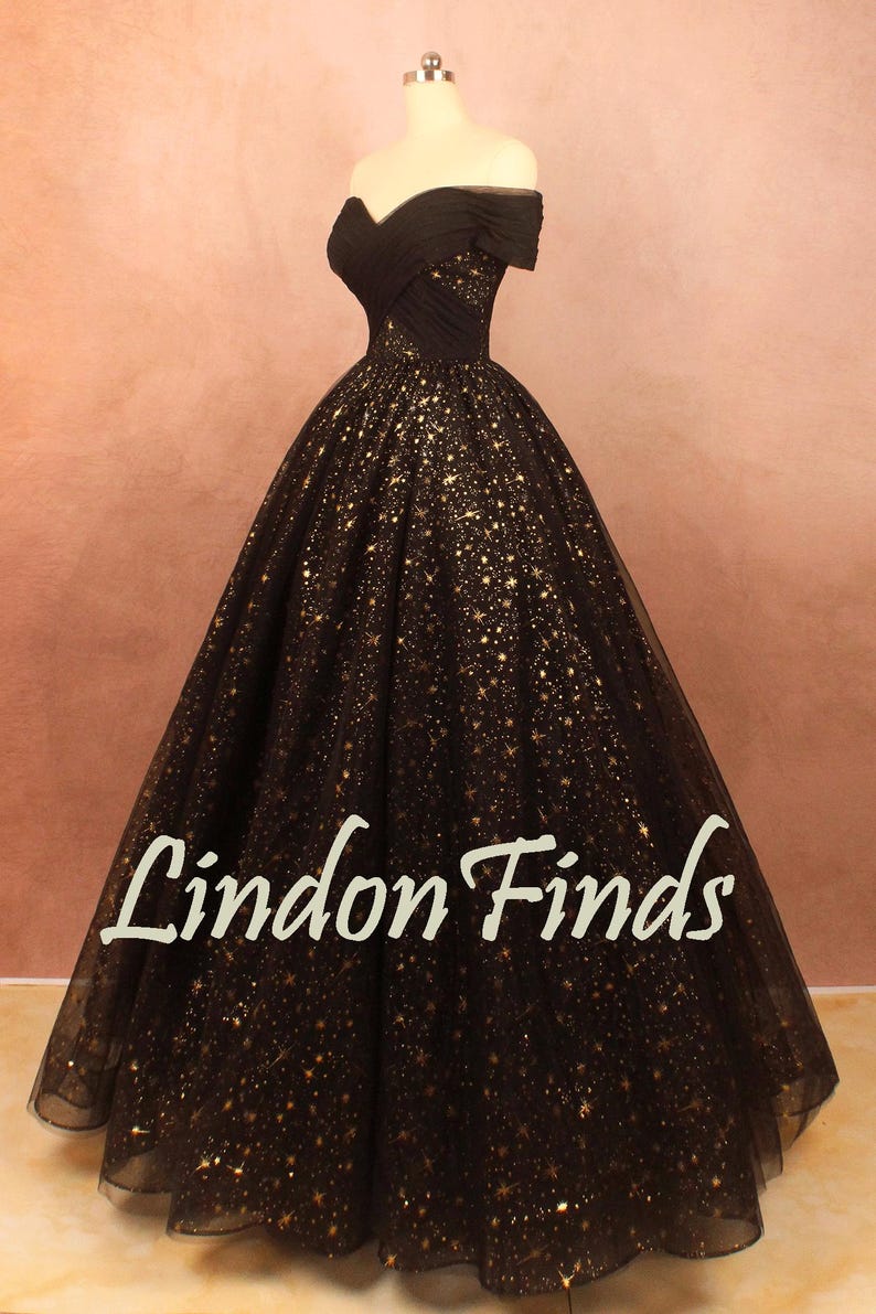 May include: A black off-the-shoulder gown with a full skirt, adorned with gold star-shaped embellishments. The dress is displayed on a mannequin. The text "Lindon Finds" is visible on the skirt.