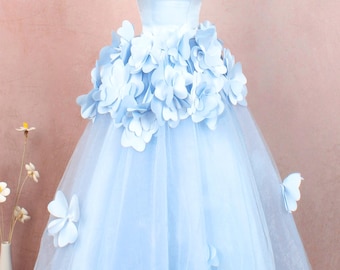 May include: A light blue tulle dress with a strapless bodice and a layer of 3D flower embellishments. The dress has a full skirt and is perfect for a special occasion.