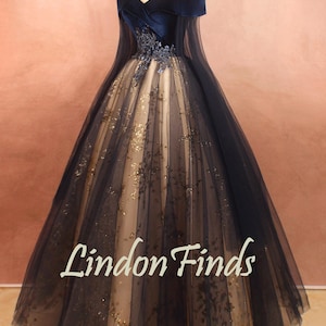 May include: A formal gown with a navy blue velvet bodice and off-the-shoulder sleeves. The skirt is a full ballgown style with layers of tulle and gold glitter accents. The text "Lindon Finds" is visible on the skirt.
