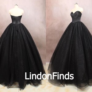 May include: A black strapless ball gown with a fitted bodice and a full skirt. The skirt is made of tulle and has a sparkly finish.