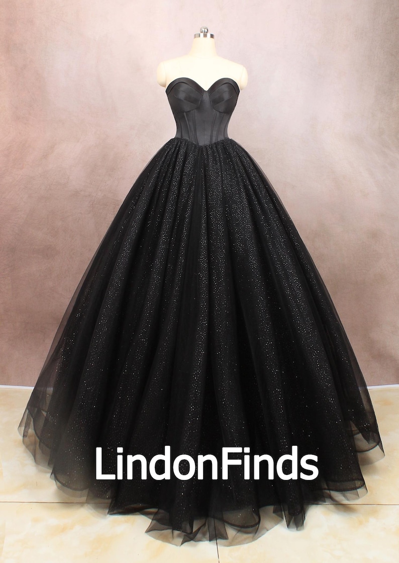 May include: A black strapless ball gown with a fitted bodice and a full skirt made of tulle with glitter. The gown is on a mannequin and the skirt is flowing out around it. The text "LindonFinds" is visible at the bottom of the image.