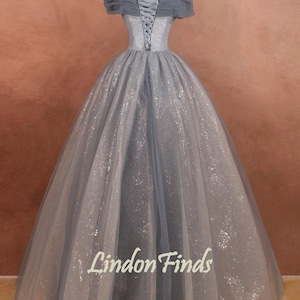 K&ouml;nnte beinhalten: Ein hellblaues T&uuml;ll-Ballkleid mit Schn&uuml;rung im R&uuml;cken und tr&auml;gerlosen Schultern. Das Kleid ist mit silbernem Glitzer verziert.