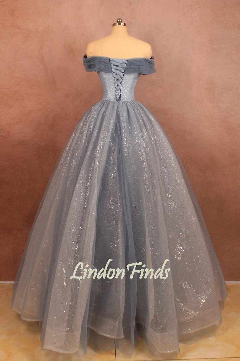 K&ouml;nnte beinhalten: Ein hellblaues T&uuml;ll-Ballkleid mit Schn&uuml;rung im R&uuml;cken und tr&auml;gerlosen Schultern. Das Kleid ist mit silbernem Glitzer verziert.