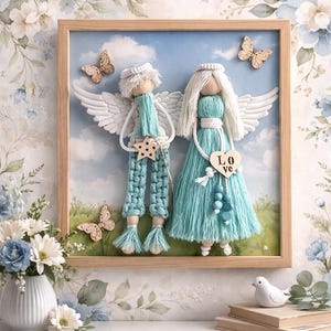 May include: A framed artwork features two handmade angel figures with white wings and teal clothing. The angels are set against a sky background with butterflies. The word "Love" is on a wooden heart. The frame is light brown.