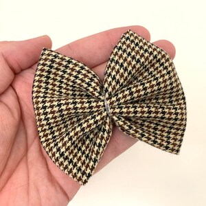 May include: A brown, black, and cream plaid bow with a houndstooth pattern.