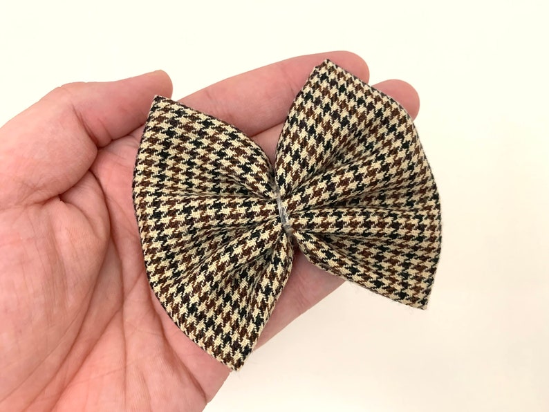 May include: A brown, black, and cream plaid bow with a houndstooth pattern.