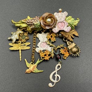 Unusual vintage chandelier brooch in antique gold tone with dangles including teddy bears, treble clef, flower, swallow bird, dragonfly