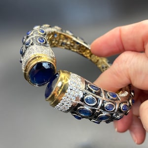 Brazalete articulado de estilo etrusco, con incrustaciones de diamantes de imitación azul zafiro y transparente, en tono dorado vintage y cuadrados de esmalte negro.