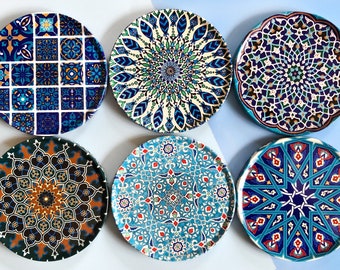 May include: Six decorative ceramic plates with intricate blue, green, and gold geometric patterns. The plates feature a variety of designs, including floral motifs, starbursts, and geometric shapes.