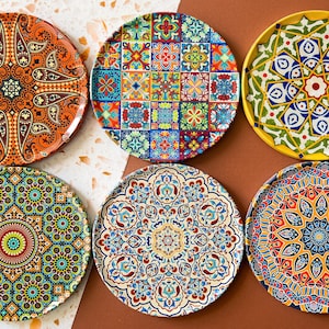 Puede incluir: Seis platos decorativos con coloridos patrones geométricos. Los platos presentan diseños intrincados en tonos de azul, verde, naranja, amarillo y rojo.