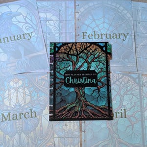 May include: A personalized planner with a tree design on the cover, featuring the text "THIS PLANNER BELONGS TO: Christina." Surrounding pages display months like January, February, and March, with illustrations of a raven and butterfly.