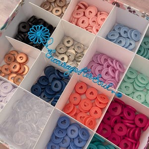 May include: A square organizer box with twelve compartments filled with colorful plastic disc-bound planner discs, each featuring a central heart-shaped cutout. A blue wire script reading "encourage her soul" is placed over the center.
