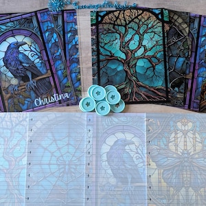 May include: A collection of planner covers and inserts with a stained-glass theme. The covers feature images of a raven, a tree, and a butterfly. The inserts have lined pages and matching designs. Includes light blue disc-shaped binding elements. The name "Christina" is visible on one cover.