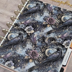 May include: A disc-bound planner featuring a dark, celestial-inspired cover pattern with black ravens, purple roses, golden crescent moons, and scattered stars. The planner includes side tabs labeled September, December, and November.