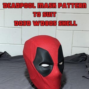 May include: A red Deadpool mask with black eye and mouth details, resting on a gray surface. The mask is the focal point, with text above and below reading "DEADPOOL MASK PATTERN TO SUIT DO3D WD805 SHELL" and "Destruction manual".
