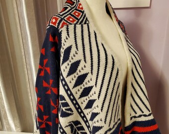 May include: A cream, navy blue, and red patterned cardigan with a draped open front. The cardigan has a geometric design with a red and white trim.
