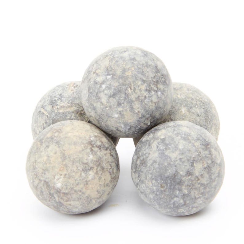 May include: Five gray stone spheres stacked in a pyramid shape. The spheres are rough and textured.