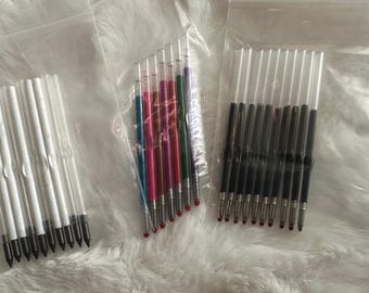 May include: Three clear plastic bags containing pen refills. One bag holds black ink refills, another holds a variety of colored ink refills, and the third holds black ink refills. The refills are in clear plastic tubes.