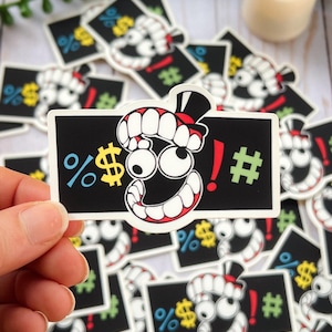 Può includere: Un adesivo rettangolare con sfondo nero raffigurante un personaggio dei cartoni animati con grandi denti bianchi, un cilindro nero e occhi spalancati. Il design include simboli colorati: un segno di percentuale blu, un segno di dollaro giallo, un punto esclamativo rosso e un hashtag verde.