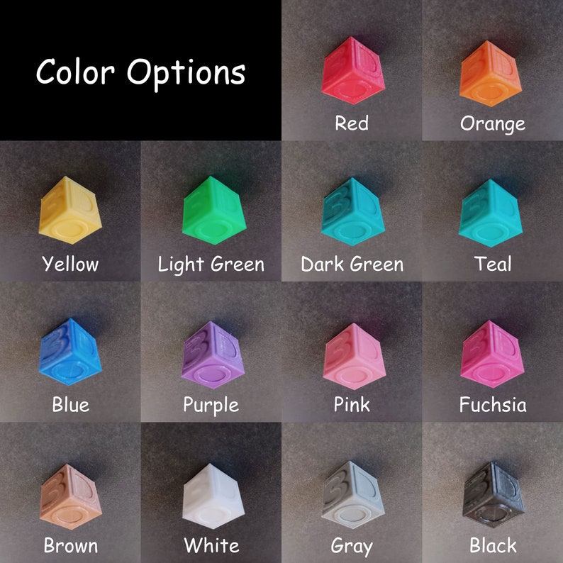 May include: Color options for a set of 12 small, cube-shaped blocks. The blocks are in the following colors: red, orange, yellow, light green, dark green, teal, blue, purple, pink, fuchsia, brown, white, gray, and black.