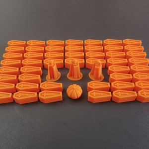 May include: A set of 36 orange plastic coffin-shaped game pieces and 5 orange plastic Halloween-themed game pieces, including a pumpkin, a ghost, and a witch.