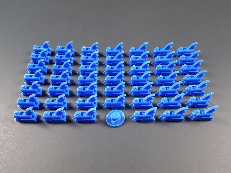 May include: A set of 40 blue plastic train engine pieces. The pieces are arranged in rows on a gray surface. There is a single blue plastic train wheel in the center of the image.