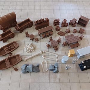 May include: A collection of miniature brown game pieces, including wagons, boats, furniture, barrels, and bones. There are also gray rocks, a yellow structure, and a black rectangular piece. The pieces are arranged on a grid.