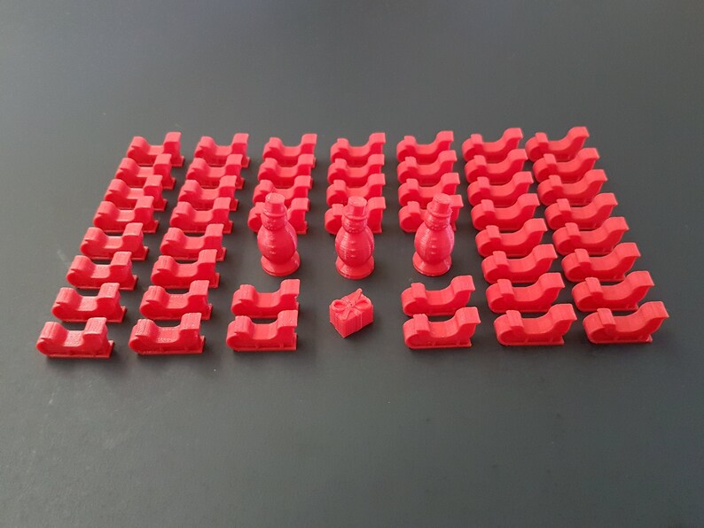 May include: A set of 3D printed red plastic Christmas sleighs and two snowman figurines. The sleighs are small and perfect for a miniature Christmas village or holiday scene.