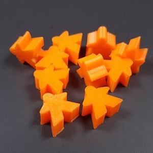 May include: A collection of orange plastic game pieces, including houses, stars, and player pieces.