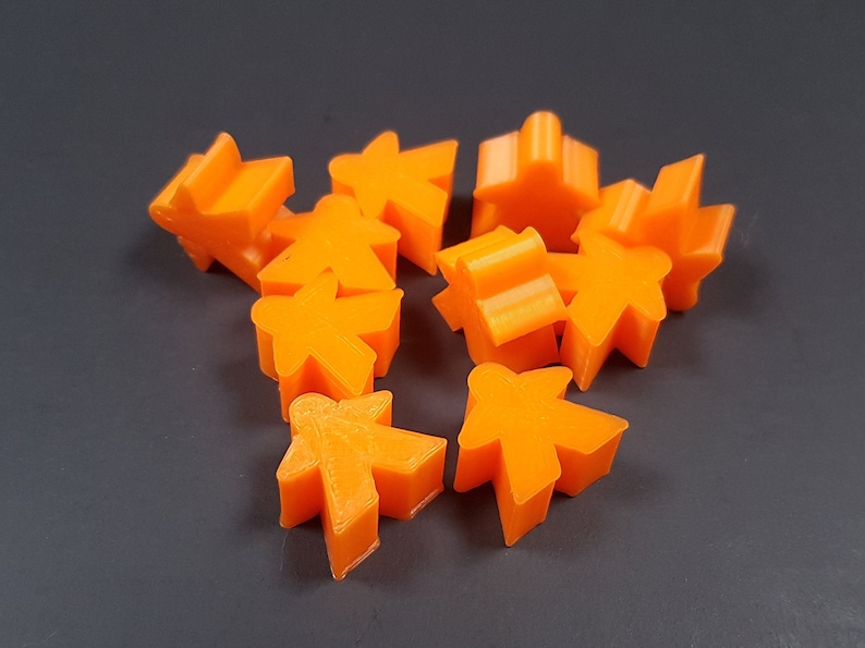 May include: A collection of orange plastic game pieces, including houses, stars, and player pieces.