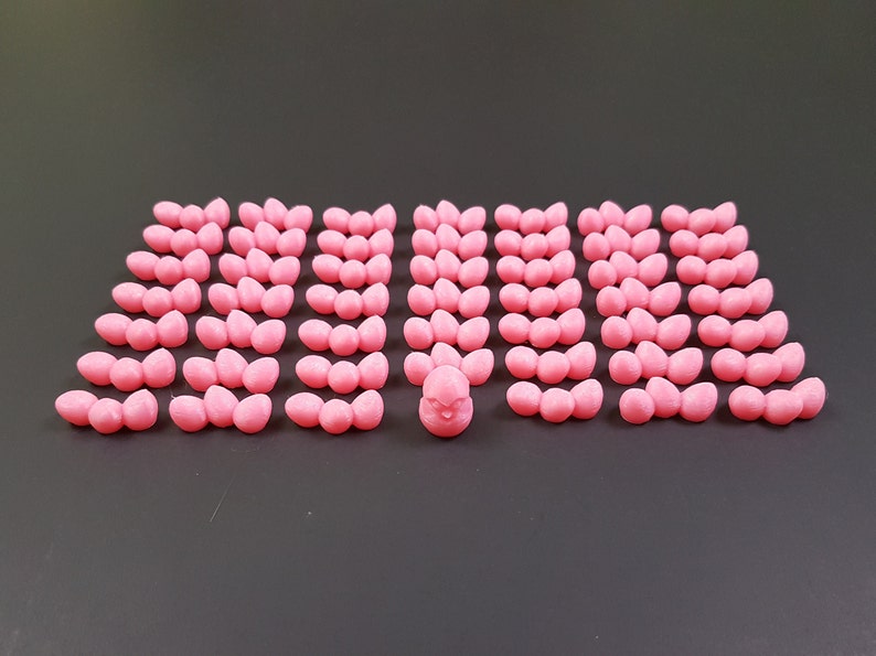 Puede incluir: Un pollito de cer&aacute;mica rosa rodeado de 40 huevos de cer&aacute;mica rosa. Los huevos est&aacute;n dispuestos en filas de tres, con el pollito en el centro.