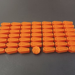 May include: A collection of 36 orange coffin-shaped Halloween decorations with one orange pumpkin-shaped decoration in the centre.