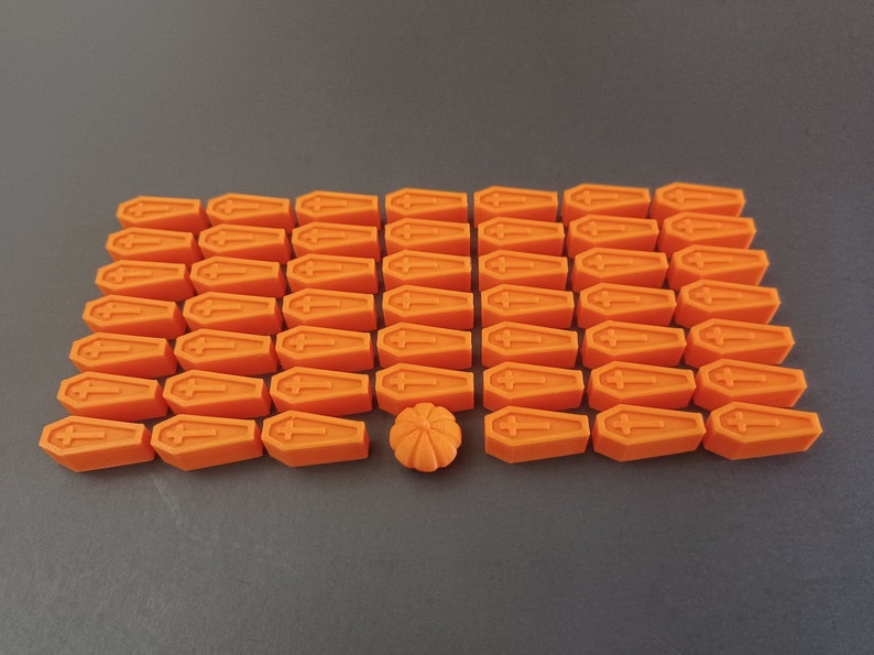 May include: A collection of 36 orange coffin-shaped Halloween decorations with one orange pumpkin-shaped decoration in the centre.