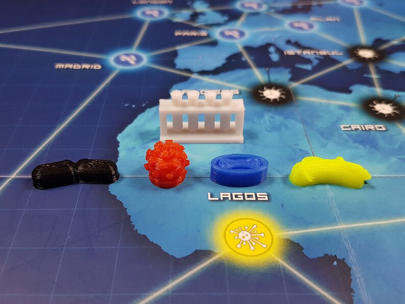 May include: A set of game pieces for the Pandemic board game. The pieces include a red virus, a black pawn, a blue research station, a yellow cure, and a white lab.