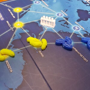 May include: A game board with a world map showing different cities. There are yellow and blue game pieces on the board. The game pieces are in the shape of small, curved cylinders. The game board also has a white plastic test tube rack.