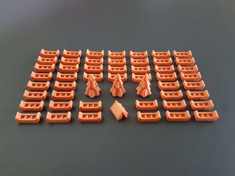 May include: A set of 40 orange canoe-shaped game pieces, 3 orange tree-shaped game pieces, and 1 orange tent-shaped game piece.