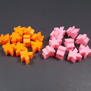 May include: A group of 12 orange and 10 pink plastic game pieces. The pieces are shaped like people.