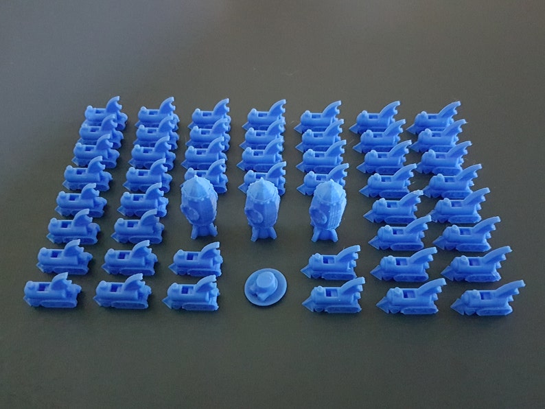 May include: A collection of 3D printed blue rocket ship figurines. There are 37 rocket ships, 3 larger rocket ships, and a small blue disc.
