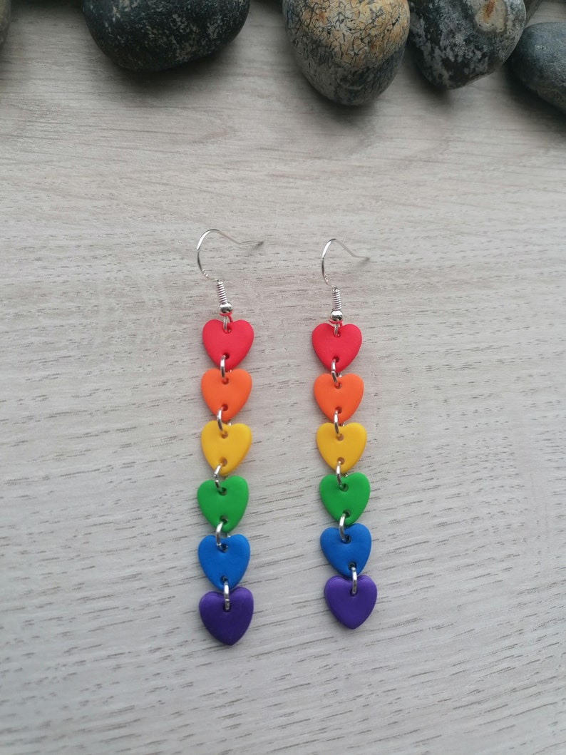 K&ouml;nnte beinhalten: Regenbogen-Herz-Ohrringe mit silbernen Haken. Jeder Ohrring hat sechs Herzen in den Farben des Regenbogens, rot, orange, gelb, gr&uuml;n, blau und lila.