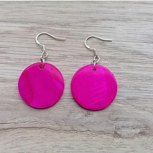 May include: A pair of pink oval earrings with silver hooks. The earrings are made of a shiny material that has a slight iridescent quality.