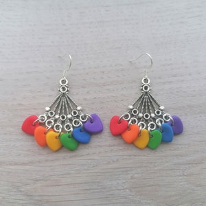 Könnte beinhalten: Regenbogen-Herz-Ohrringe mit einer silbernen Kette und einem Haken. Jeder Ohrring hat sieben Herzen in den Farben des Regenbogens.