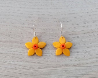 May include: A pair of yellow flower earrings with orange centers. The earrings are made of polymer clay and have silver hooks.